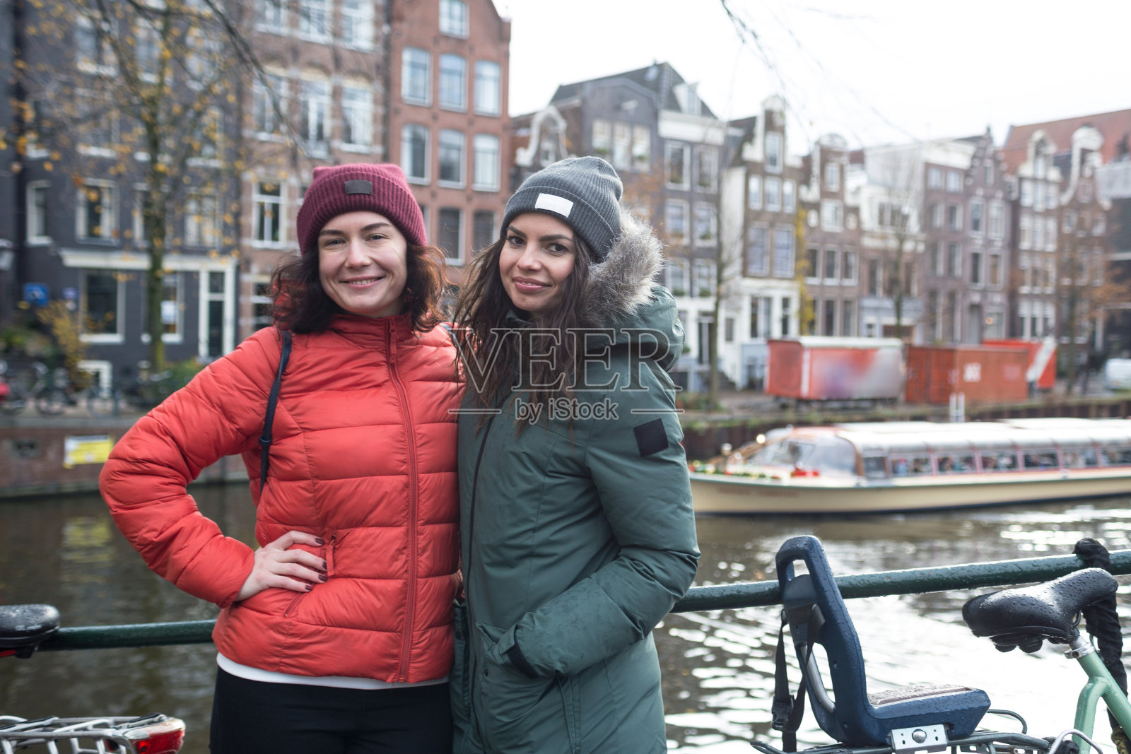 女朋友们站在阿姆斯特丹的运河附近。冬天他们在城市里散步。照片摄影图片
