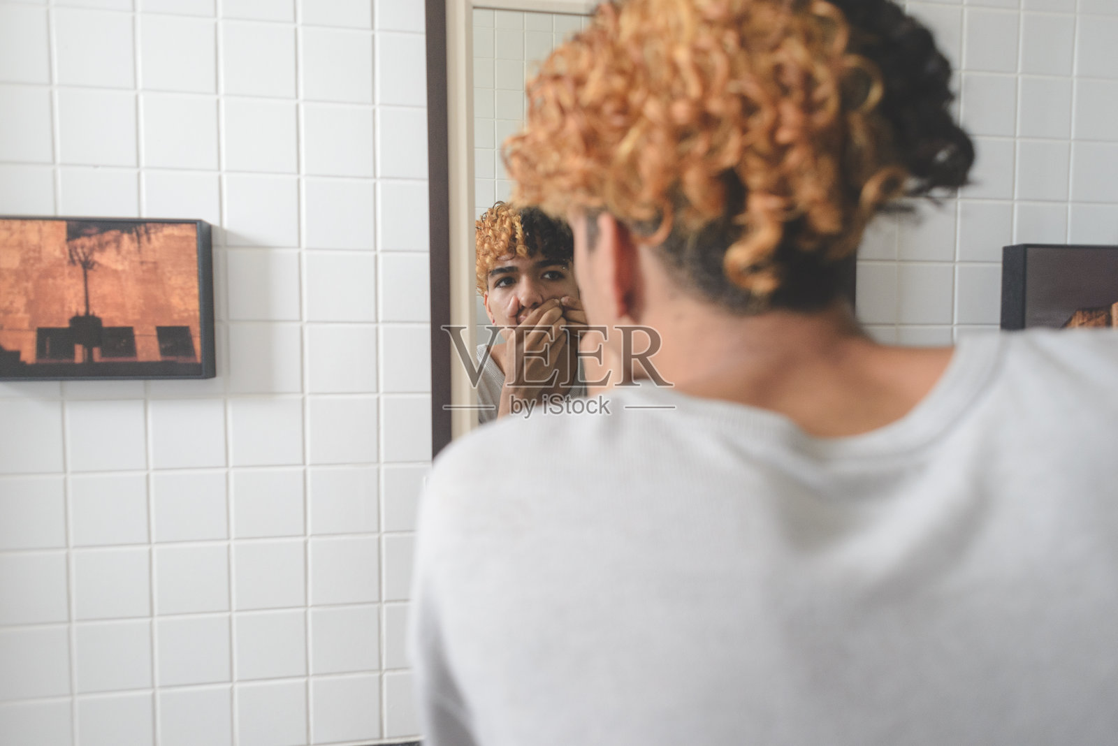 青少年在浴室的镜子前挤青春痘照片摄影图片