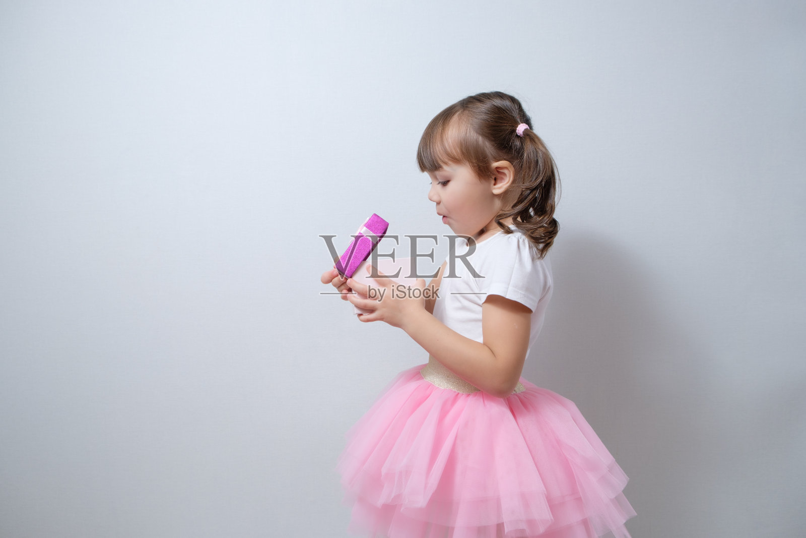 面带惊讶表情的小女孩在礼品盒里寻找惊喜：新年快乐，圣诞快乐，生日快乐照片摄影图片