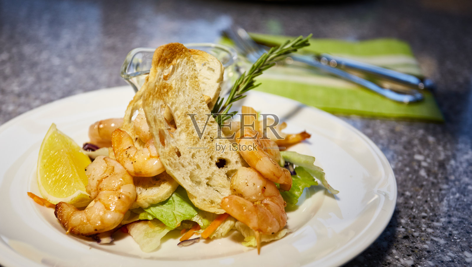 烤虾放在白色的盘子里，配上吐司，柠檬和酱汁，百里香枝，叶子沙拉照片摄影图片