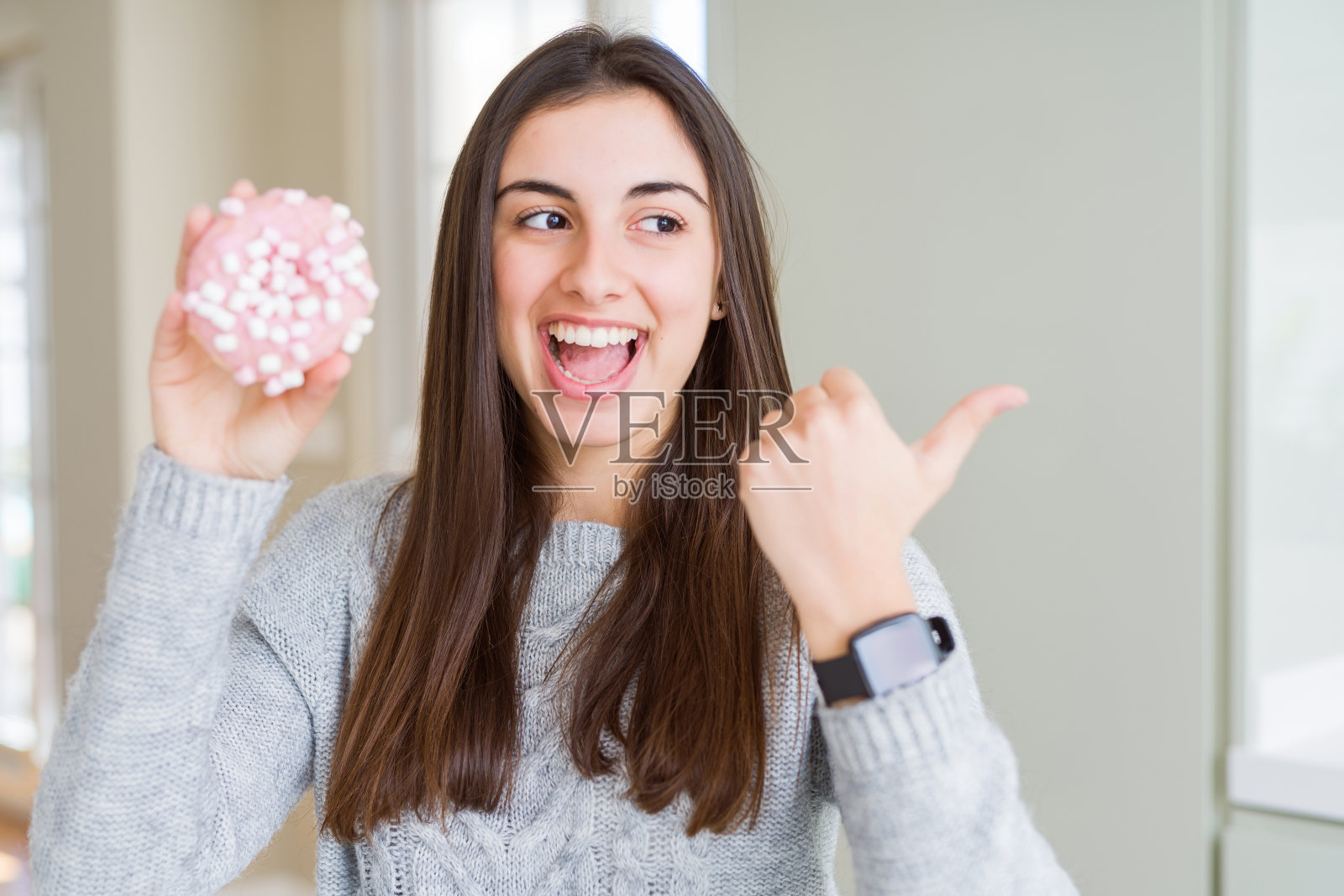 吃粉色棉花糖甜甜圈的年轻漂亮女人照片摄影图片