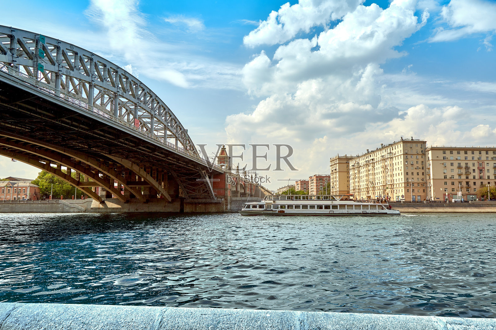 以城市大桥为背景的现代河船。这艘船在城市河上航行，在河上美丽的城市桥梁下航行。风景如画的现代城市建筑。旅游、休息在城、河运照片摄影图片