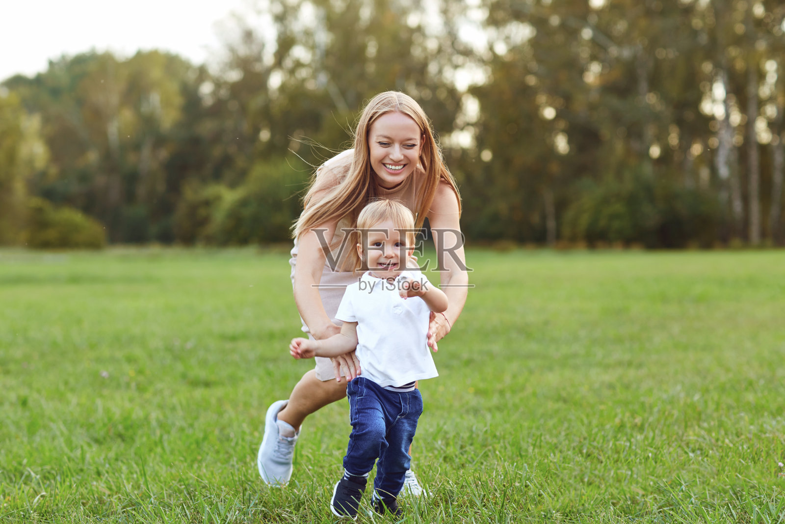 笑着的女人和小男孩在绿色的草坪上照片摄影图片