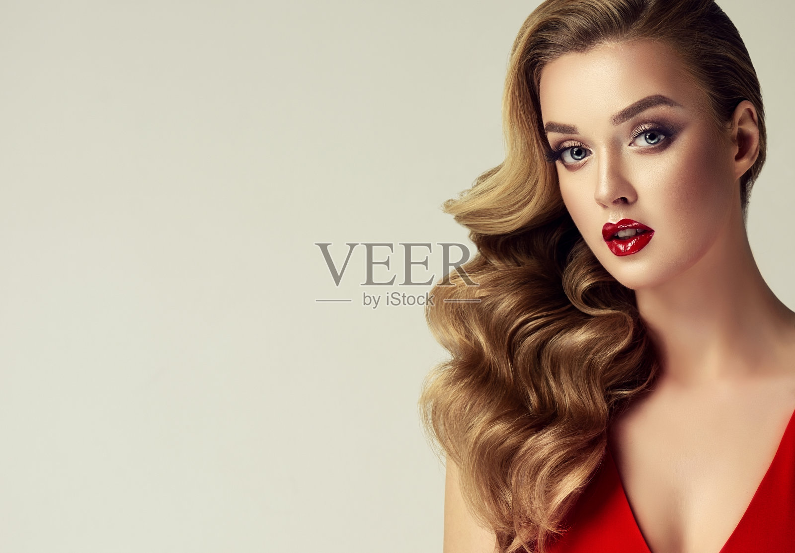 年轻迷人的女人优雅自由的卷发，穿着明亮，性感的妆容。化妆品和化妆品。照片摄影图片