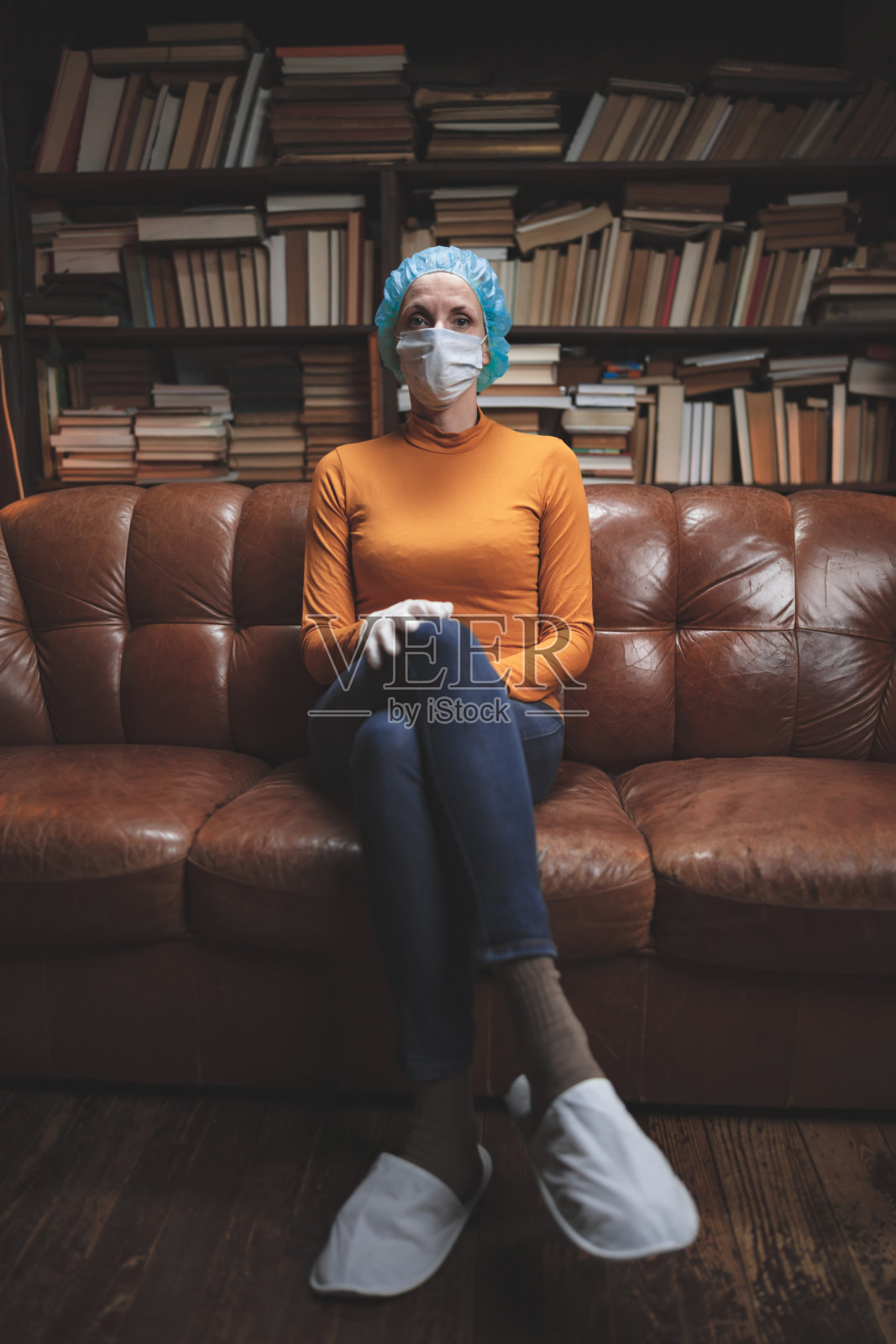 戴防护防毒口罩在家接受隔离/隔离的妇女。照片摄影图片