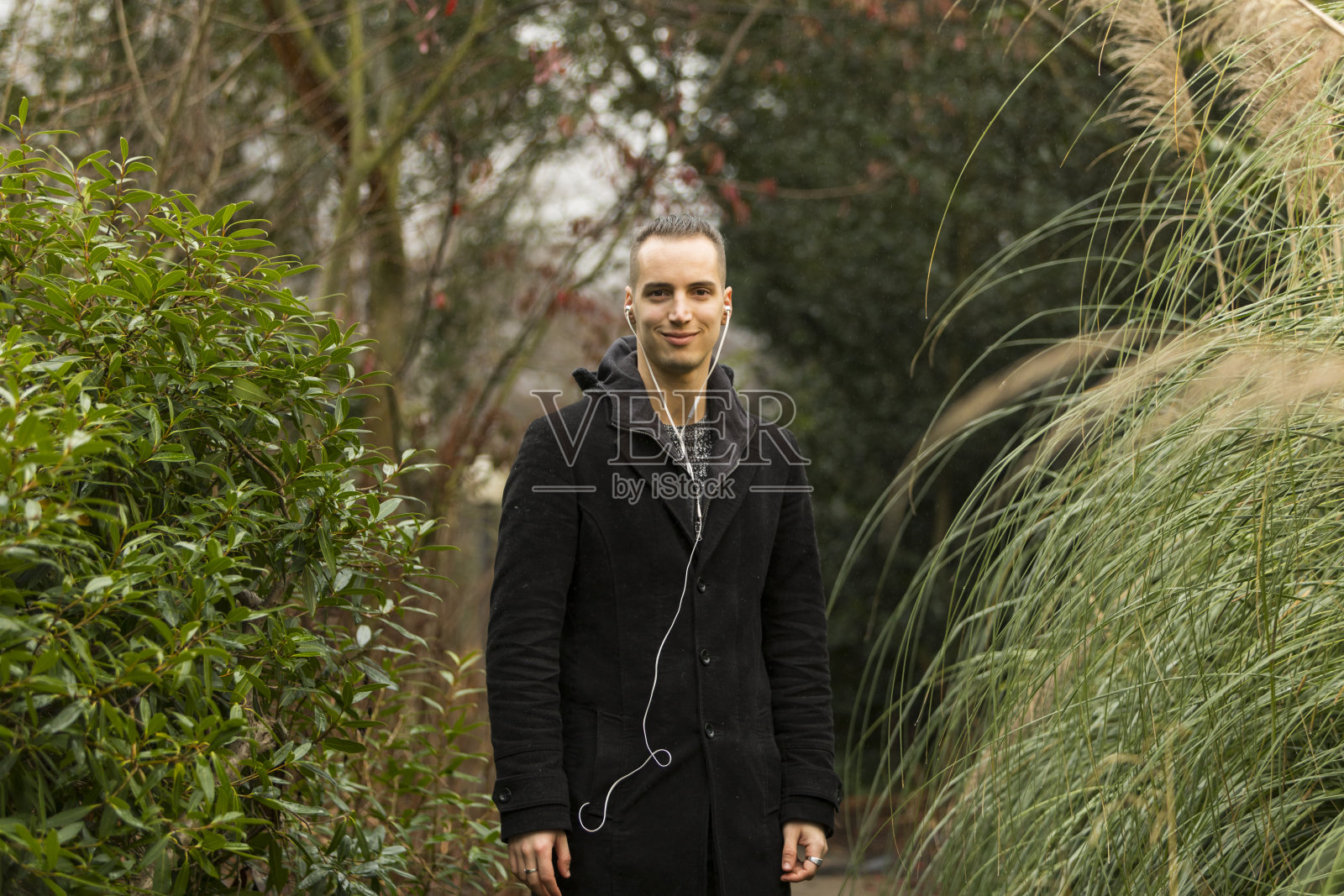 站在户外听耳机的年轻人的肖像照片摄影图片