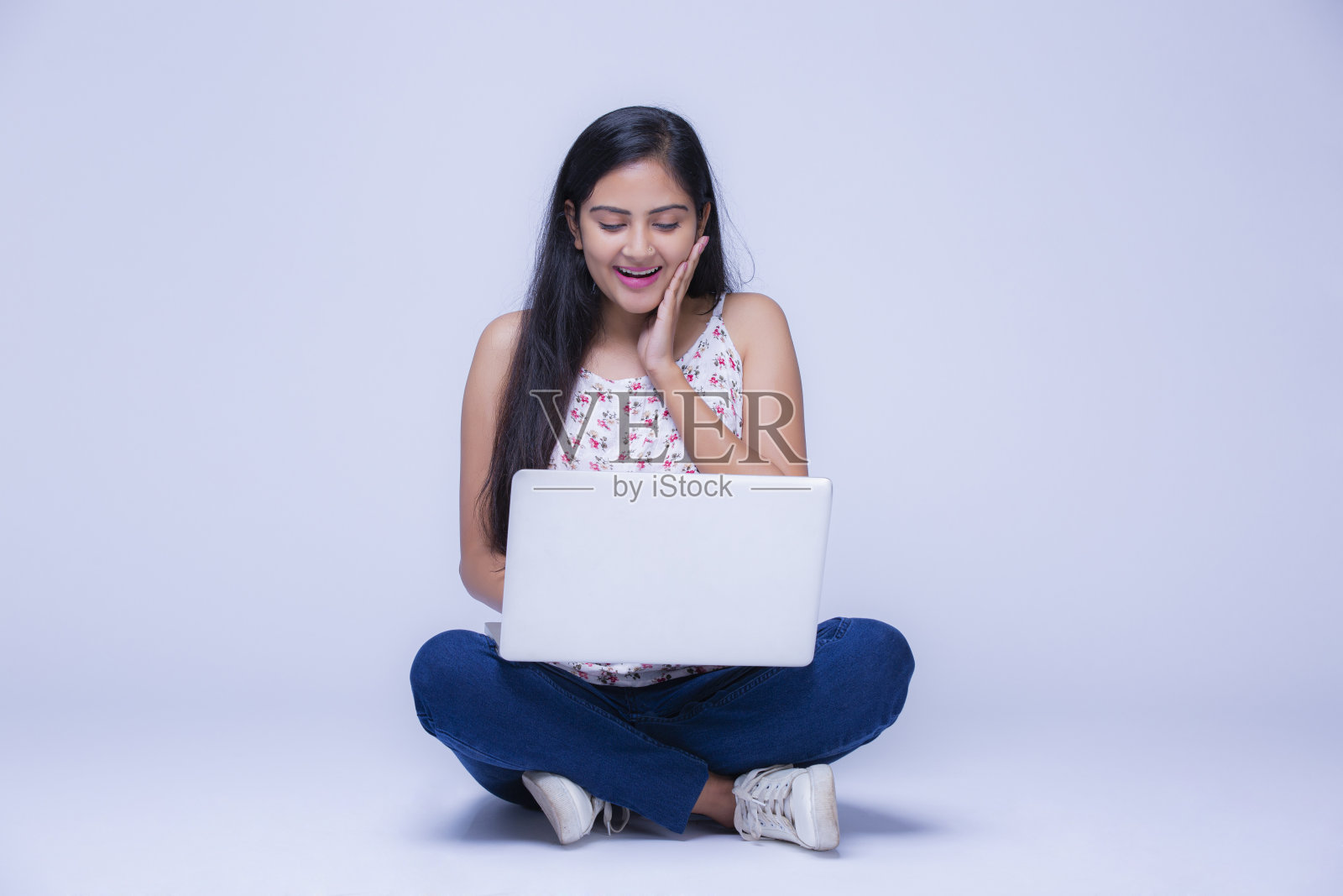 在白色背景下使用笔记本电脑的年轻女孩照片摄影图片