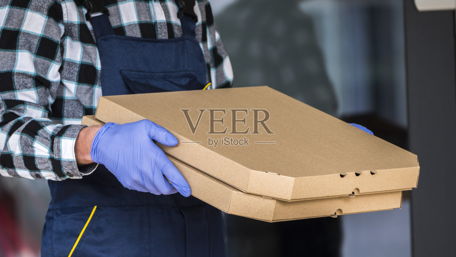 安全递送披萨，快递员用防护手套拿着盒子。侧视图照片摄影图片