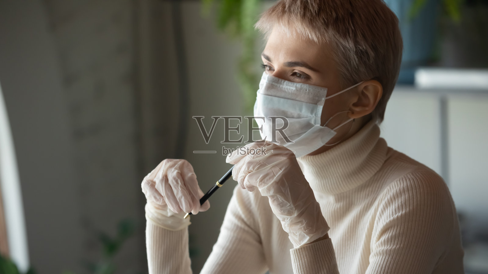 沉思的年轻女商人在医疗手套和保护性面罩。照片摄影图片