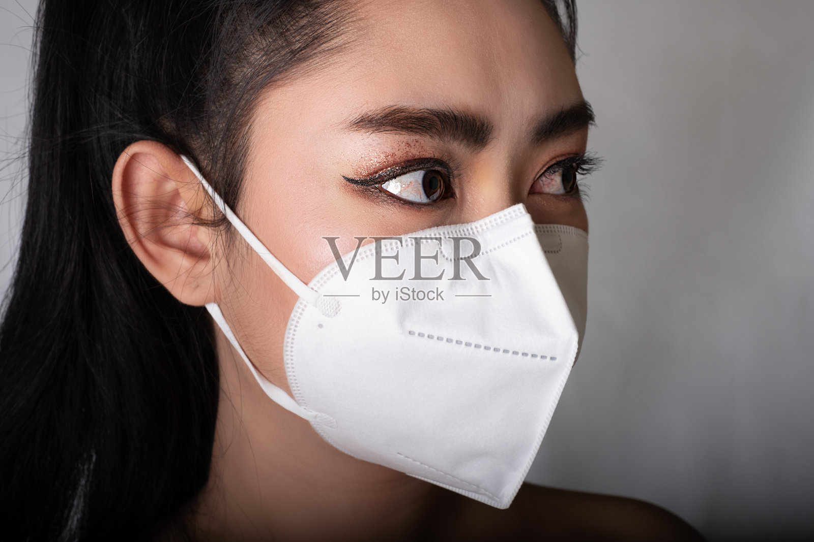 一名戴着N95口罩的妇女的特写，以保护免受流感covid-19冠状病毒埃博拉PM2.5粉尘和雾霾等空气传播的呼吸道疾病，安全病毒感染概念，照片摄影图片