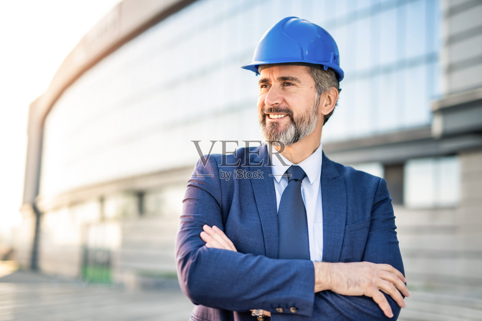 快乐成熟的工程师双手交叉看着别处。照片摄影图片