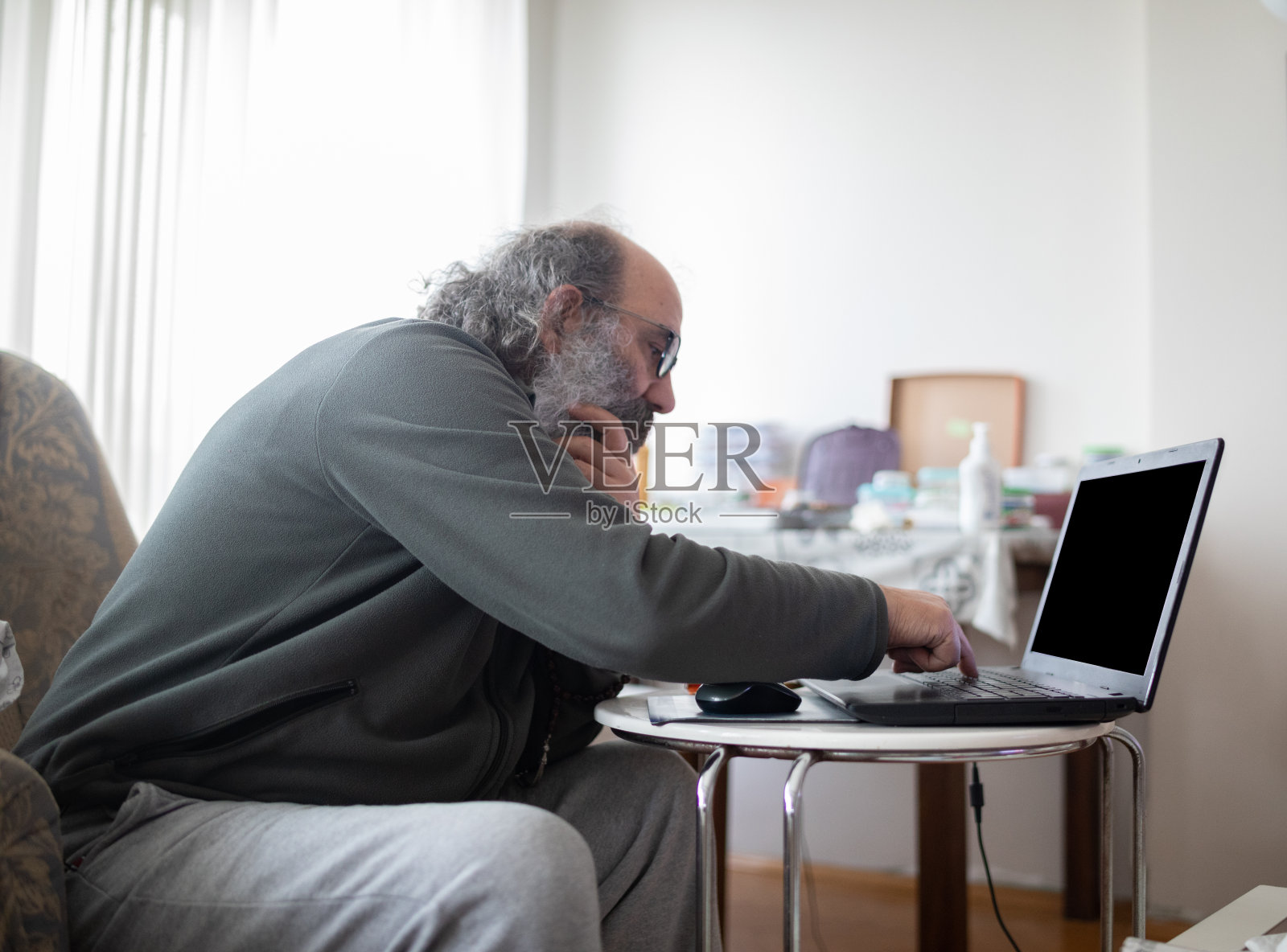 年长男性在家中使用电脑，他正在隔离自己照片摄影图片