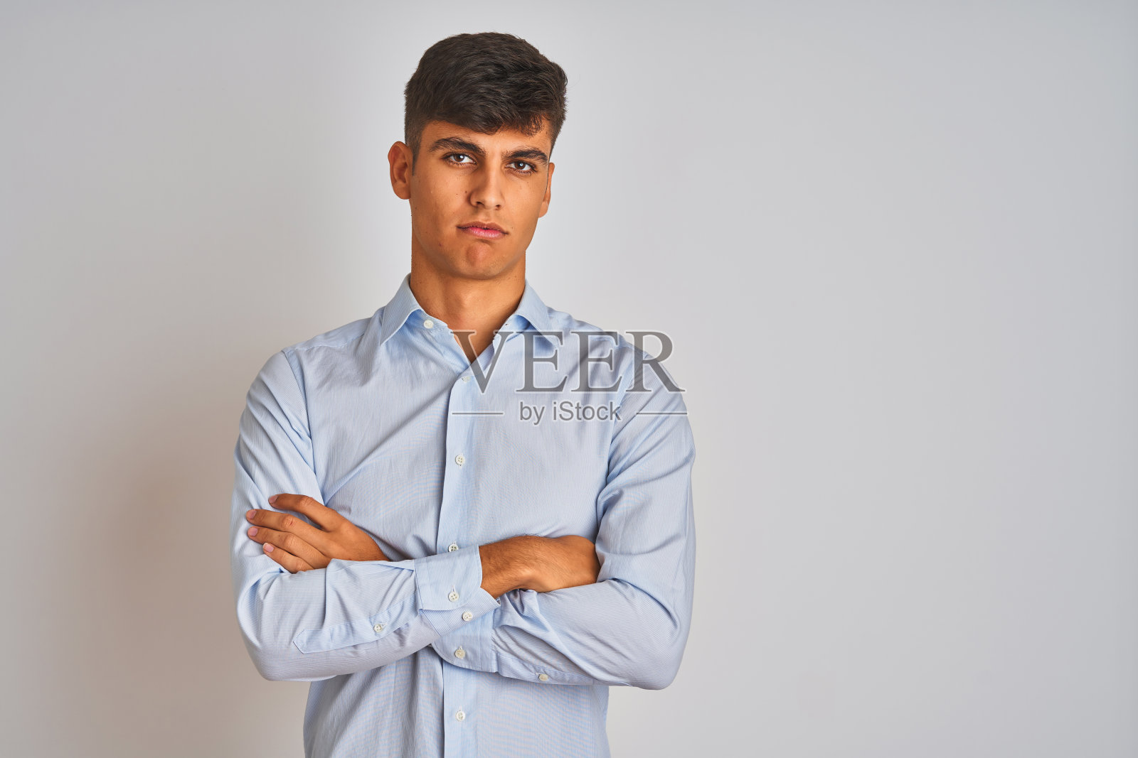 身穿衬衫的印度商人站在白色背景前，持怀疑态度，面色紧张，双臂交叉照片摄影图片