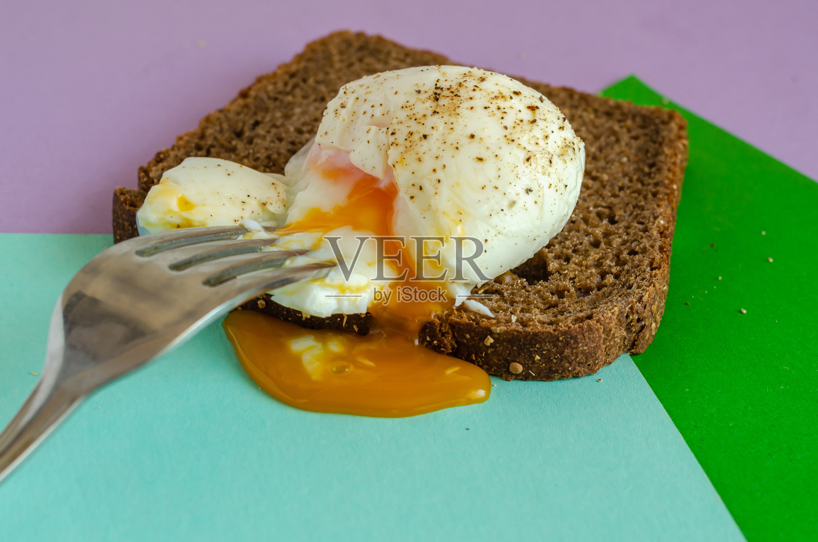 半熟鸡蛋放在一片黑麦面包上。照片摄影图片