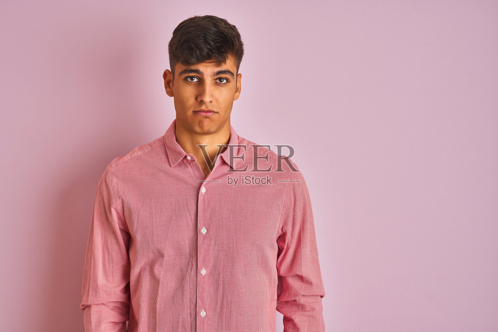 在粉色背景前，因悲伤而沮丧哭泣的年轻印度男子照片摄影图片