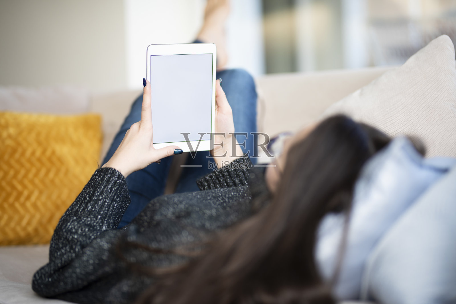 一个手里拿着平板电脑的女人在家里的沙发上休息照片摄影图片