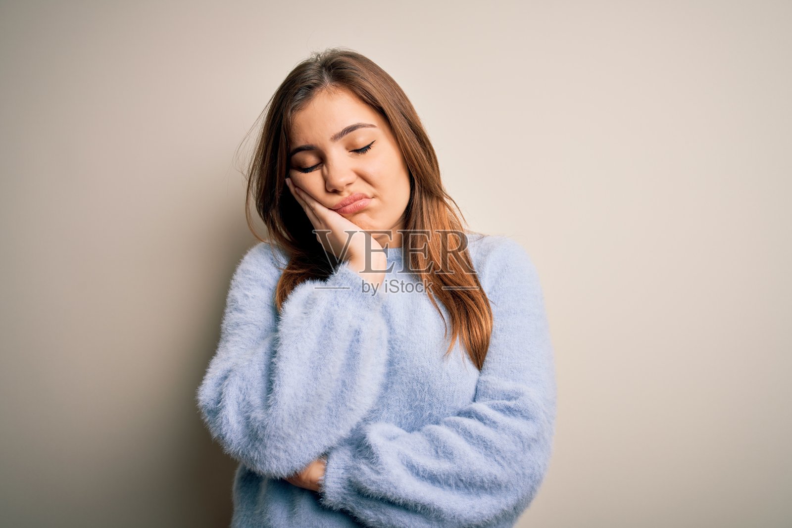 穿着休闲冬装的年轻漂亮女人，背景为孤立环境，交叉双臂，面露疲惫和厌烦，思考着，看起来有些沮丧。照片摄影图片