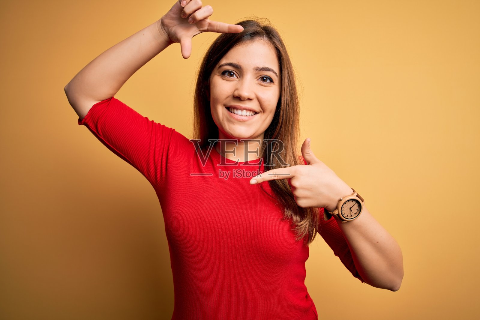 穿着红色休闲T恤的年轻女子用手和手指开心地比心照片摄影图片