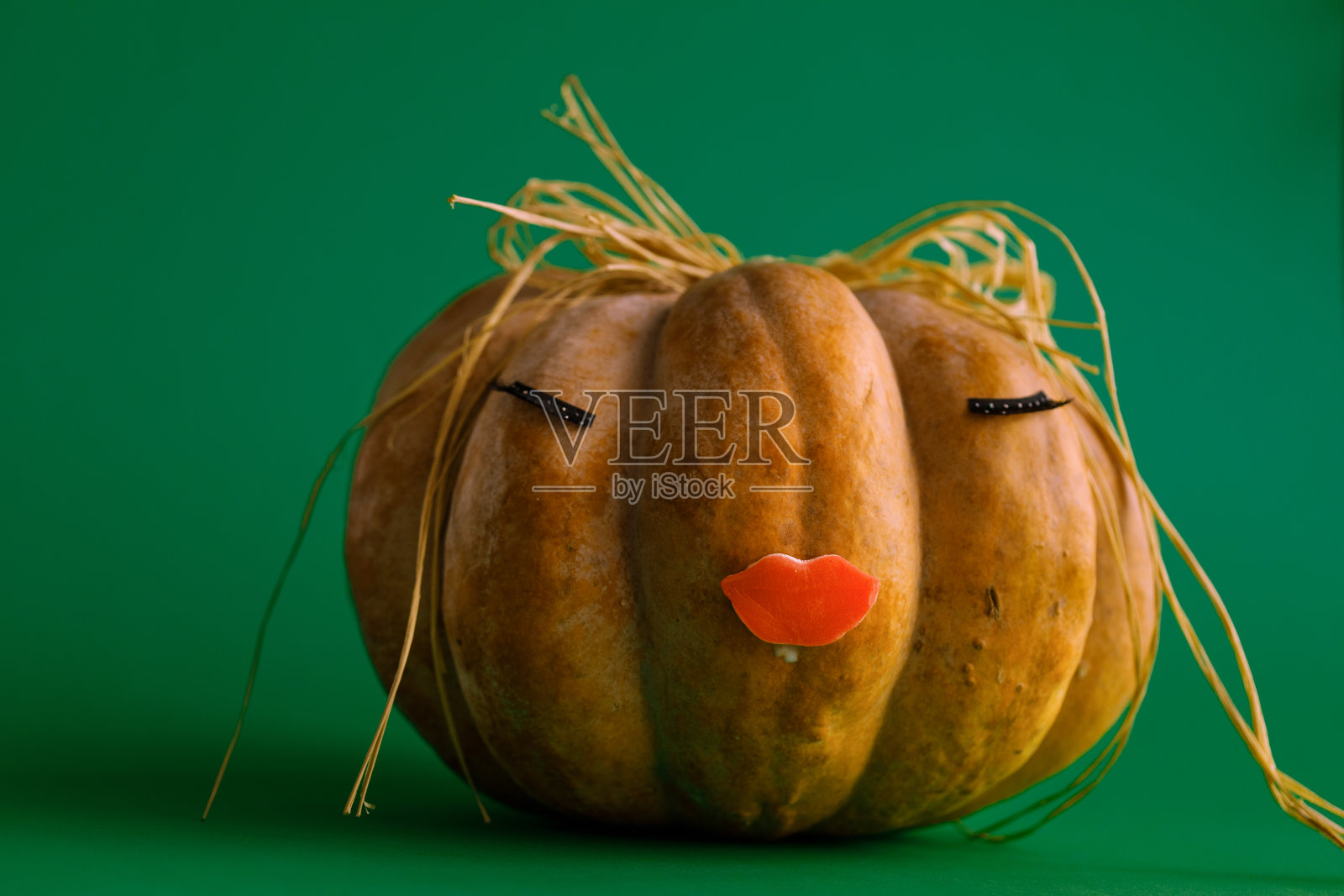 绿色背景上有睫毛和嘴巴的南瓜照片摄影图片
