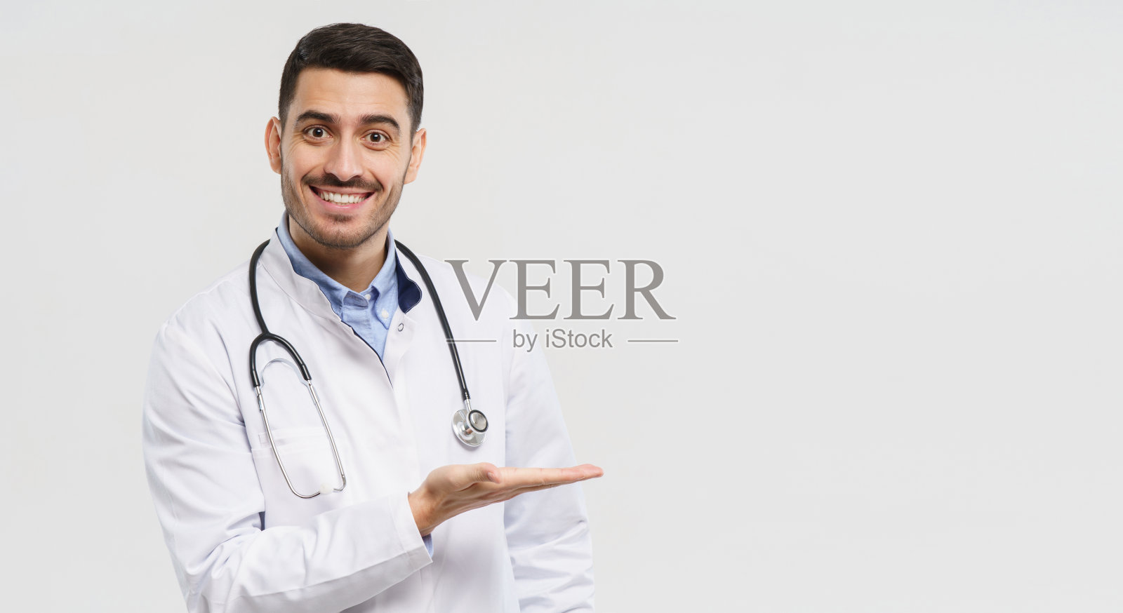 微笑的年轻男医生用手展示和展示一些东西的横旗，孤立在灰色背景上，右侧有拷贝空间照片摄影图片