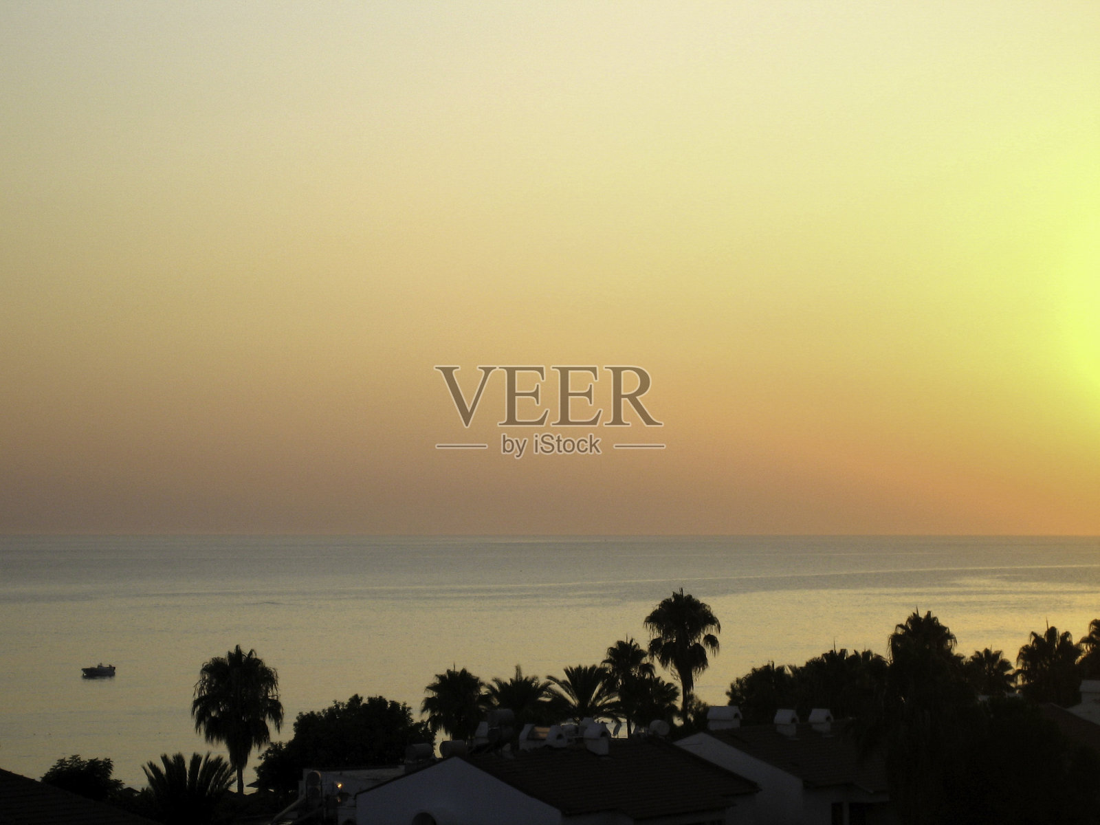 在一个宁静而晴朗的夜晚，太阳从海上的地平线上落下。照片摄影图片