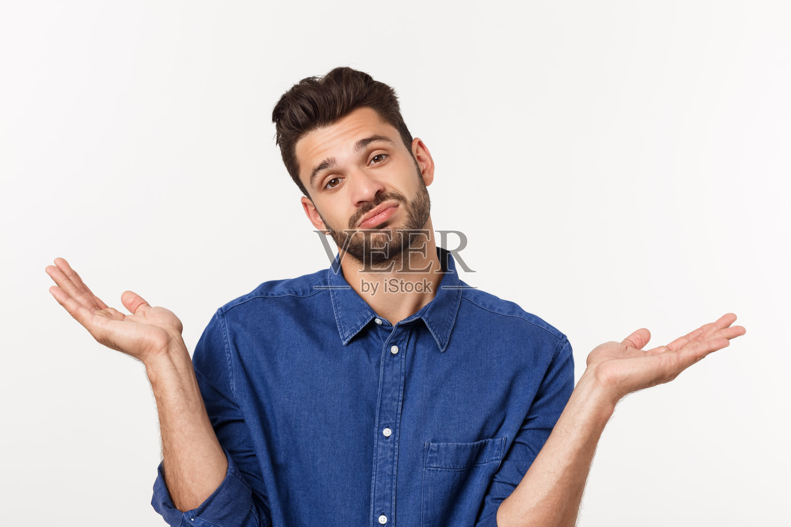 英俊的年轻商人在经典西装微笑，看着相机保持手掌向上的白色背景。商人两手空空。照片摄影图片