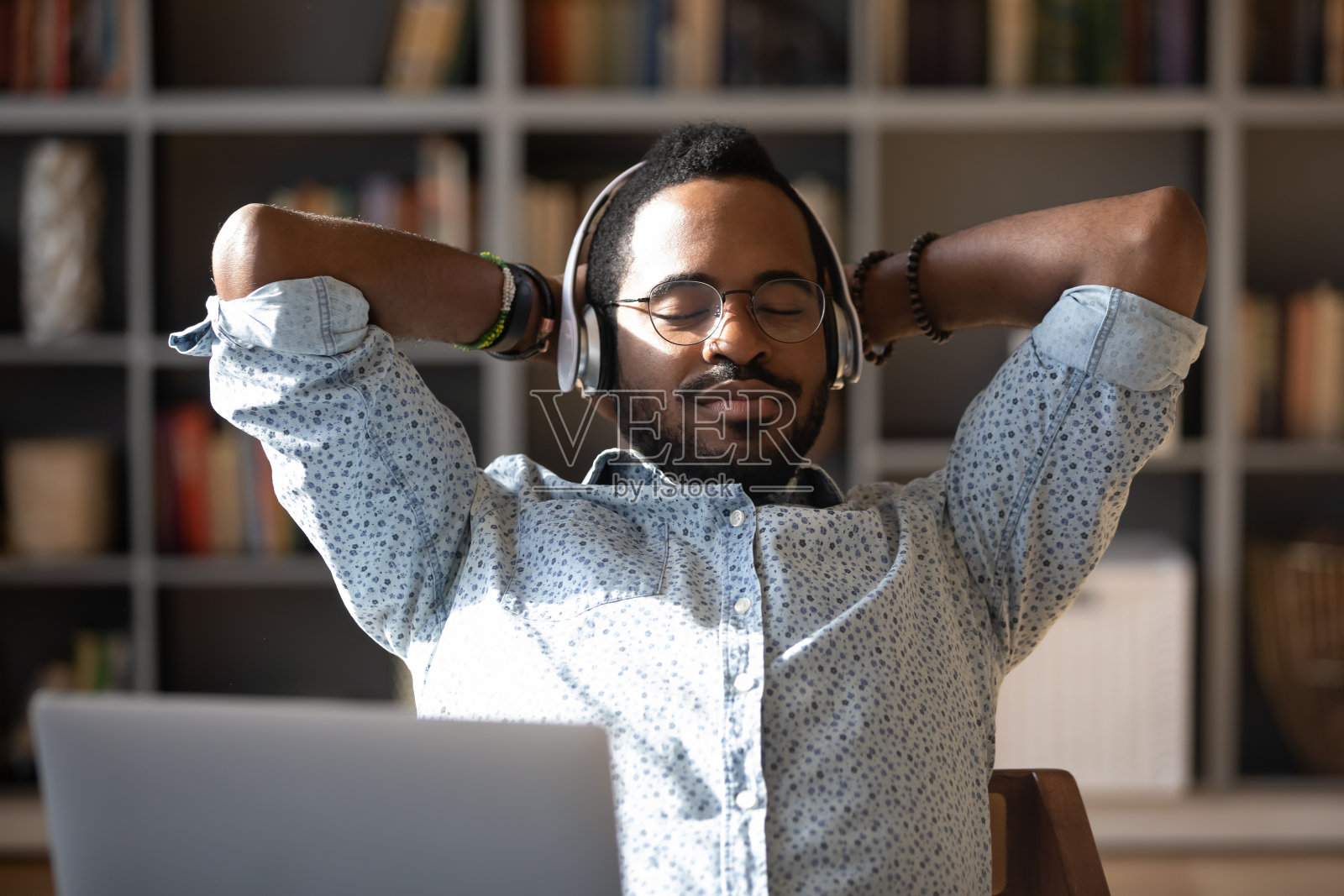 平静的年轻非洲裔美国商人放松地听着古典音乐。照片摄影图片