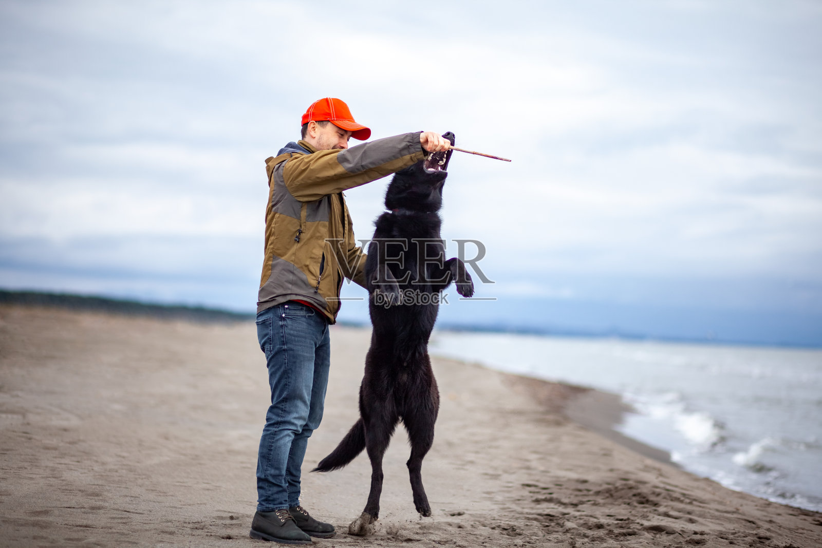 一名男子在黑海海岸的沙滩上训练德国牧羊犬照片摄影图片