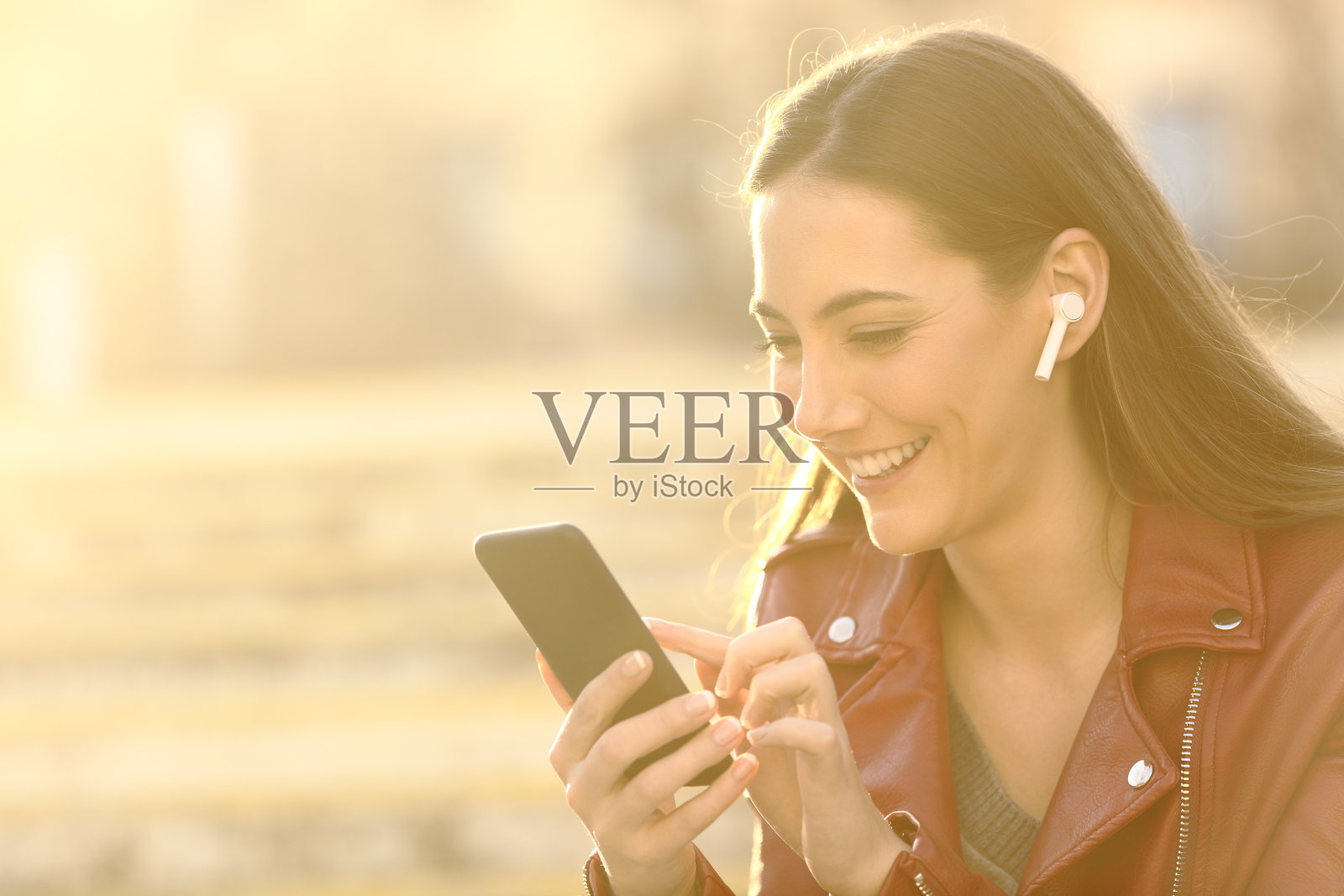 快乐的女人戴着耳机在手机上听音乐照片摄影图片