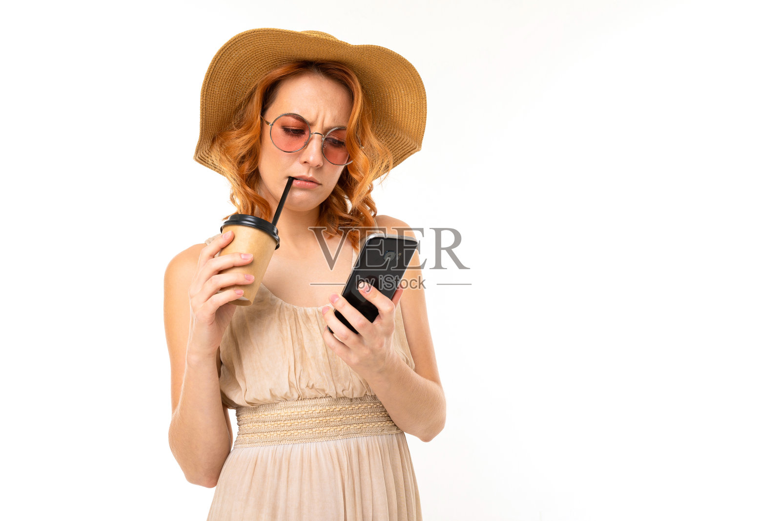 美丽的女孩在一个夏天的形象，一个手机和一杯鸡尾酒在白色的背景照片摄影图片