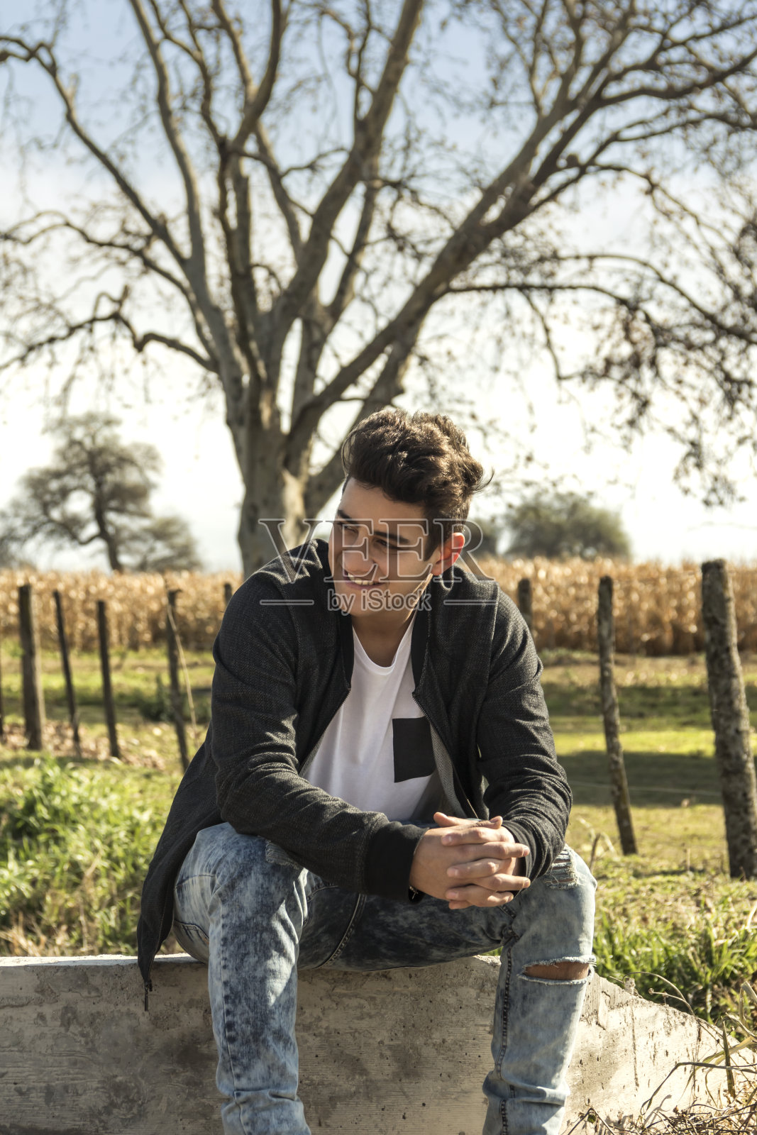 英俊的年轻人休息在一个农业地区与种植玉米的背景。阿根廷科尔多瓦。照片摄影图片