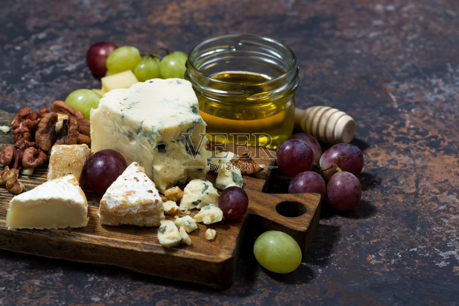 黑桌子上放着奶酪板、新鲜水果和蜂蜜照片摄影图片