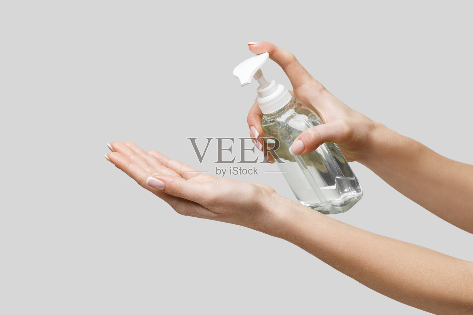 女性双手使用洗手液或肥皂液，背景为浅灰色照片摄影图片