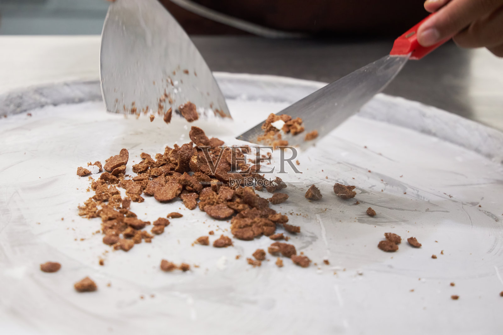 糖果商把冰淇淋的馅料放在一个冷却的金属表面上照片摄影图片