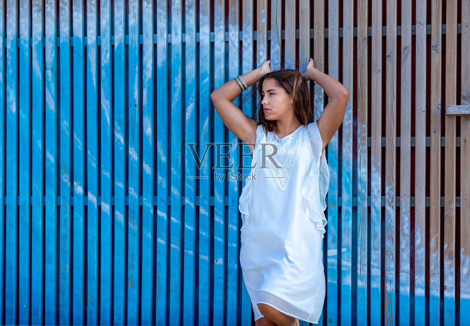 在蓝色木栅栏前的女人照片摄影图片