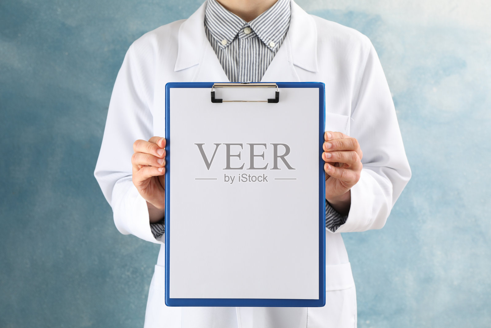 医生持有空白的平板上的蓝色背景，空白的文字照片摄影图片