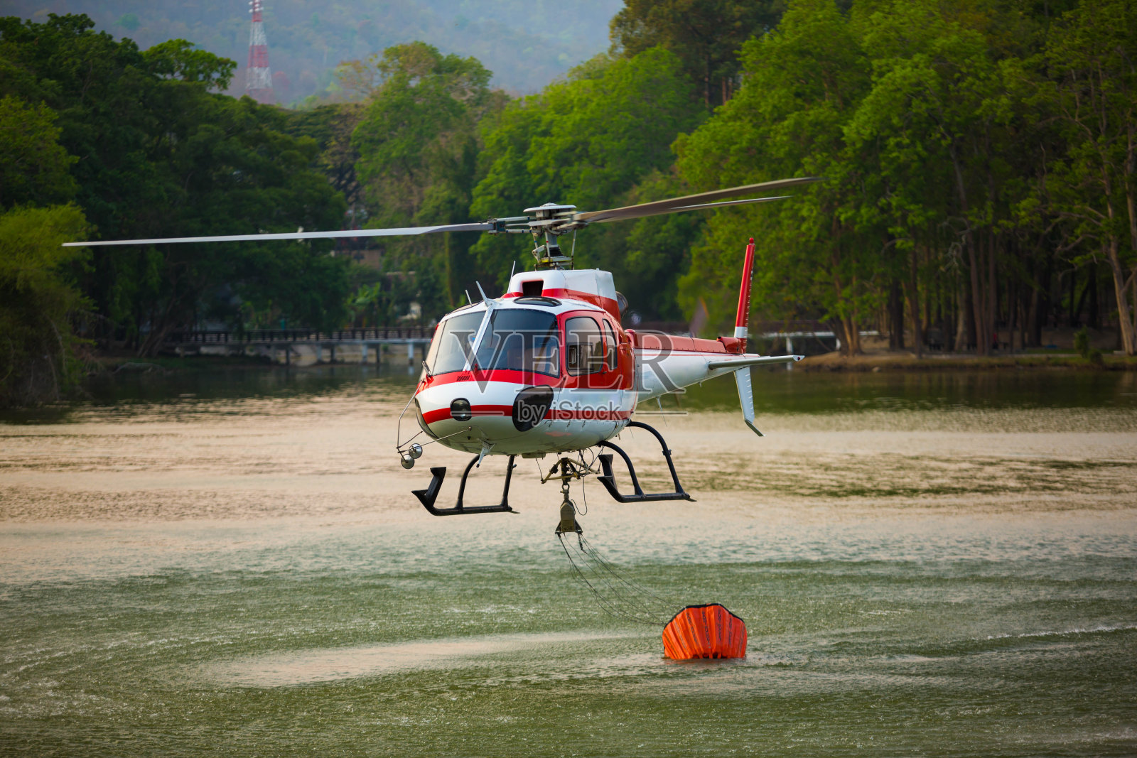 直升飞机正在从水库取水，将被用来扑灭山里燃烧的森林。照片摄影图片