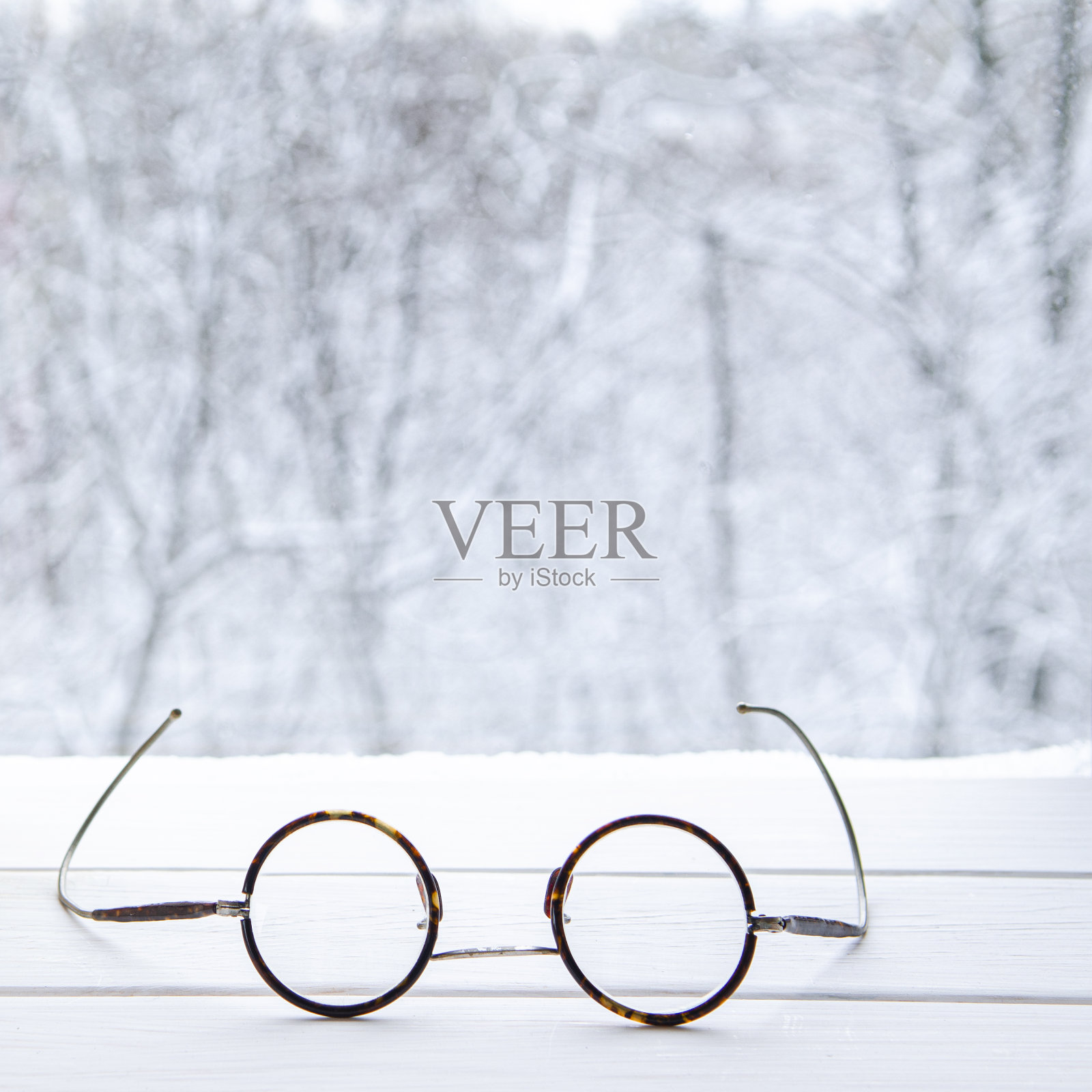 复古的圆形老花镜躺在白色的窗台上，背景是一片森林照片摄影图片