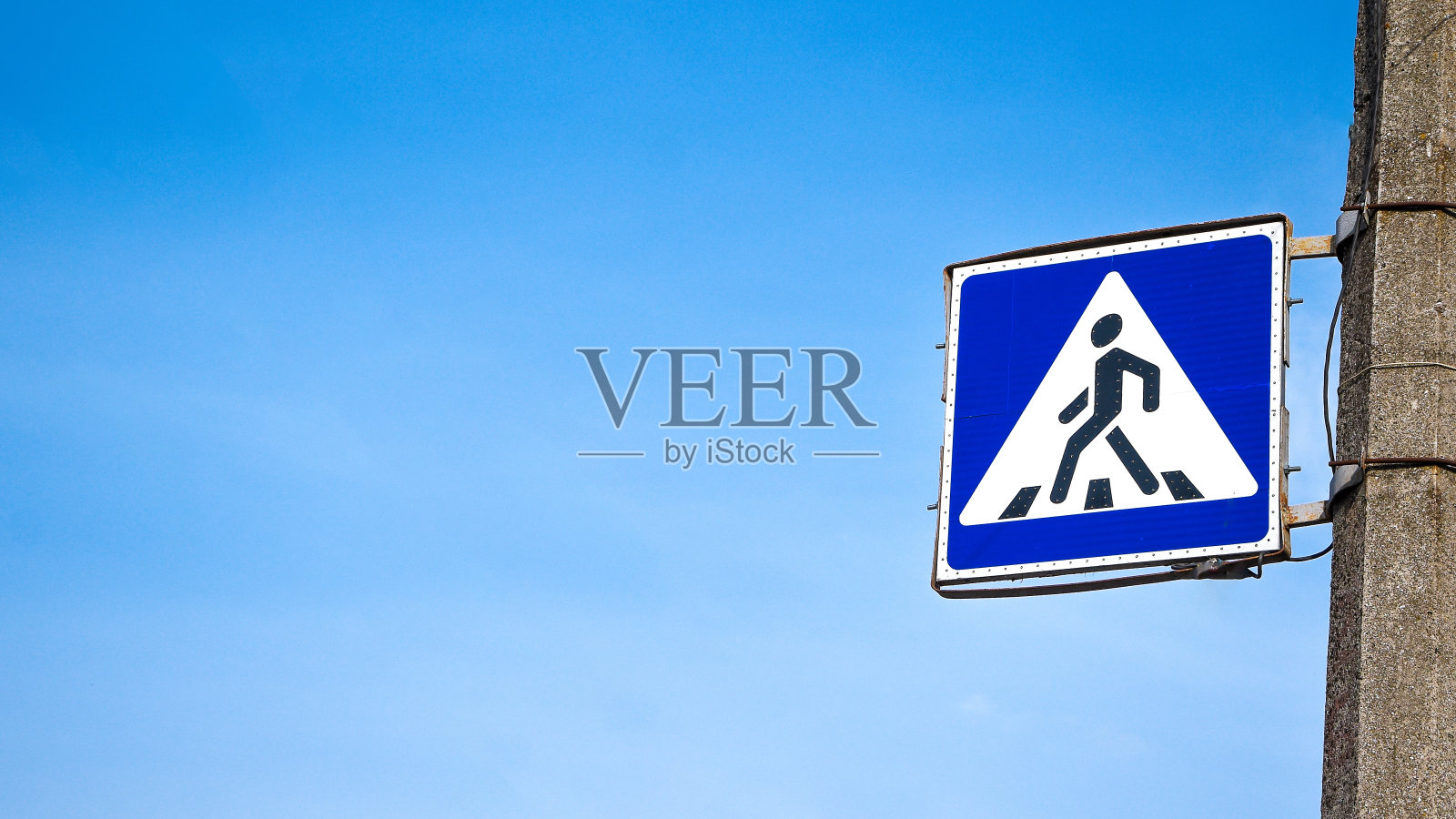 人行横道的垂直标志在晴朗的天空，标志的背景是蓝天照片摄影图片