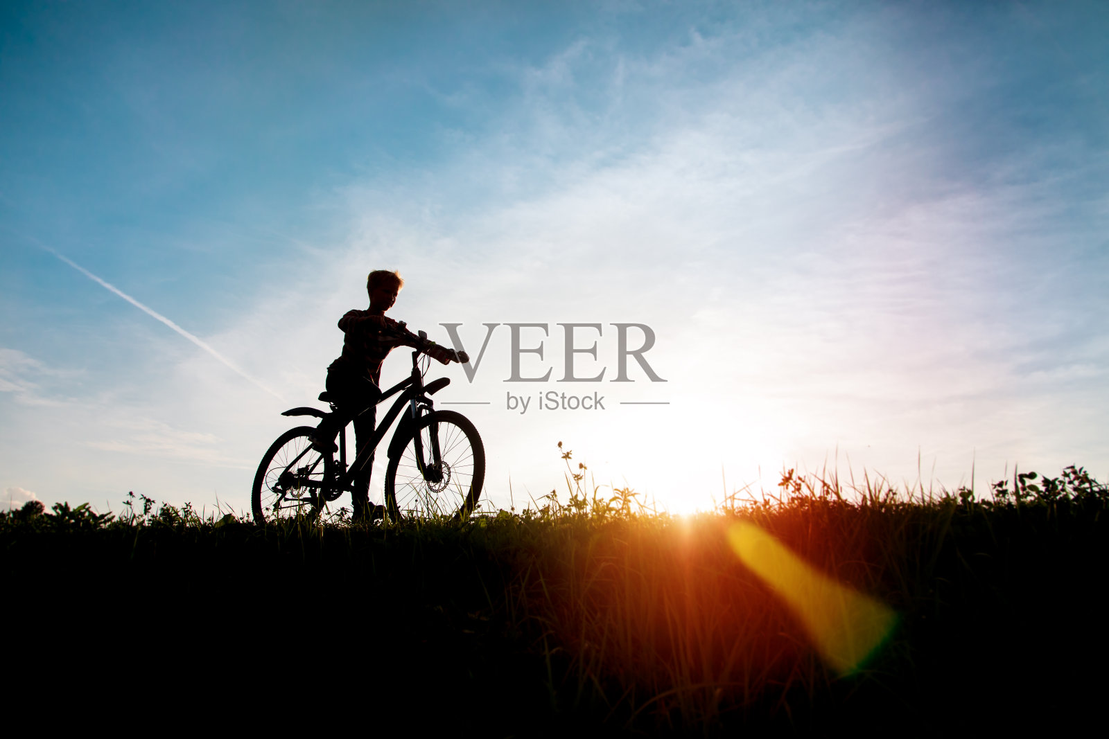 快乐的男孩骑自行车在日落的自然照片摄影图片