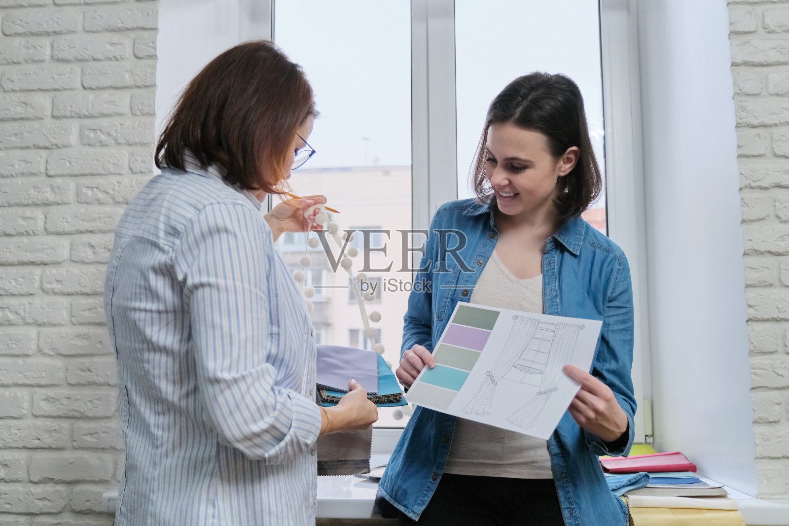 室内设计师向女客户展示窗帘和室内装饰面料的样品照片摄影图片