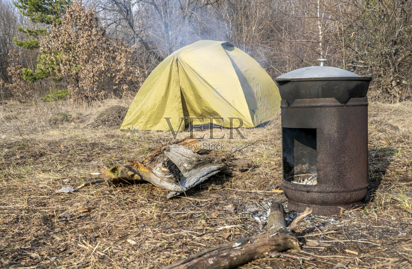 一个游客帐篷立在空地上，食物在帐篷前面的金属炉子里准备着照片摄影图片