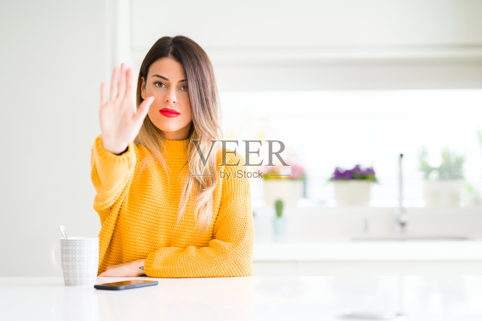 年轻漂亮的女人喝着咖啡在家做着手心停止唱歌。警告表情与否定和严肃的手势在脸上。照片摄影图片