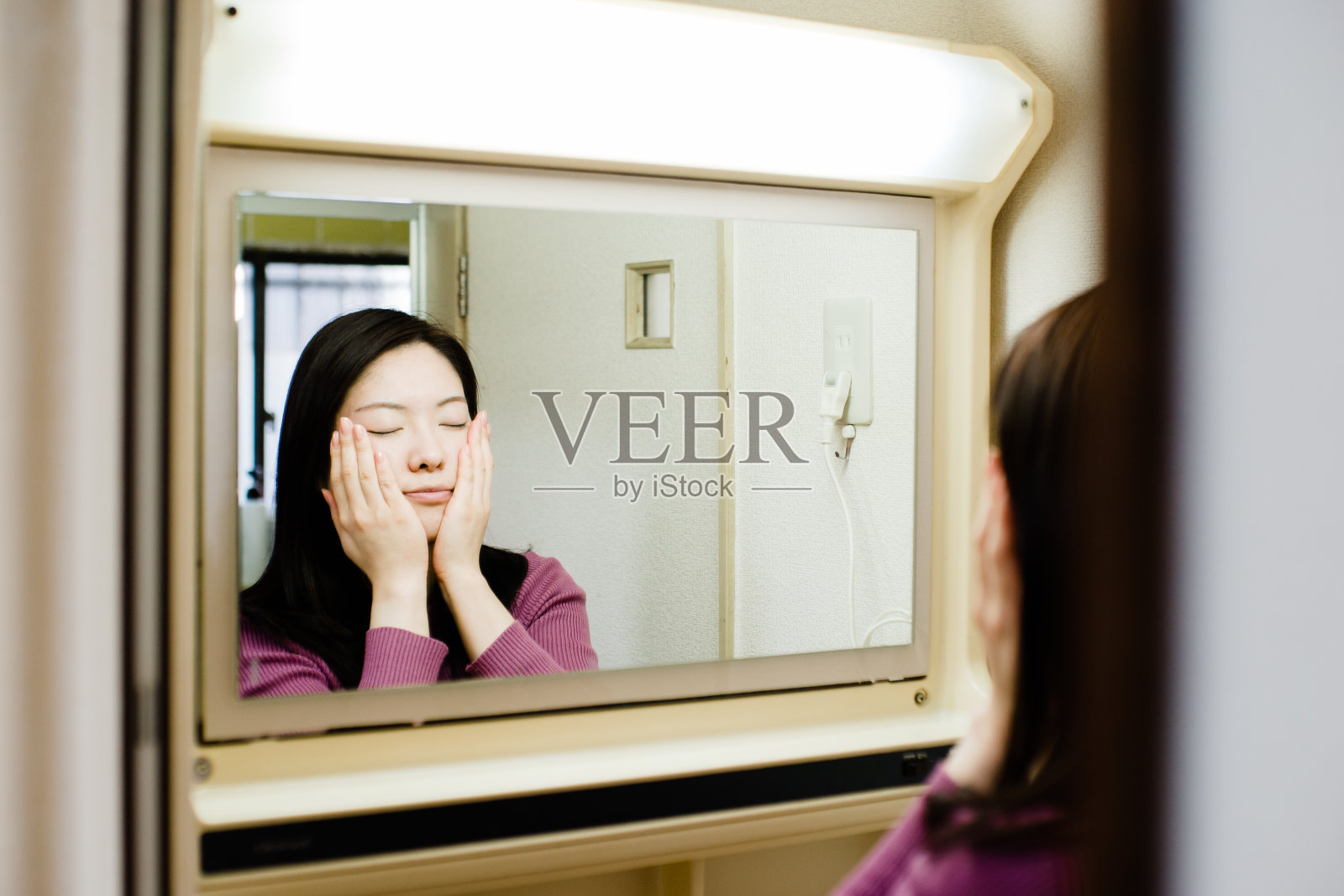 透过镜子拍摄的亚洲女性在浴室做美容护理的照片照片摄影图片