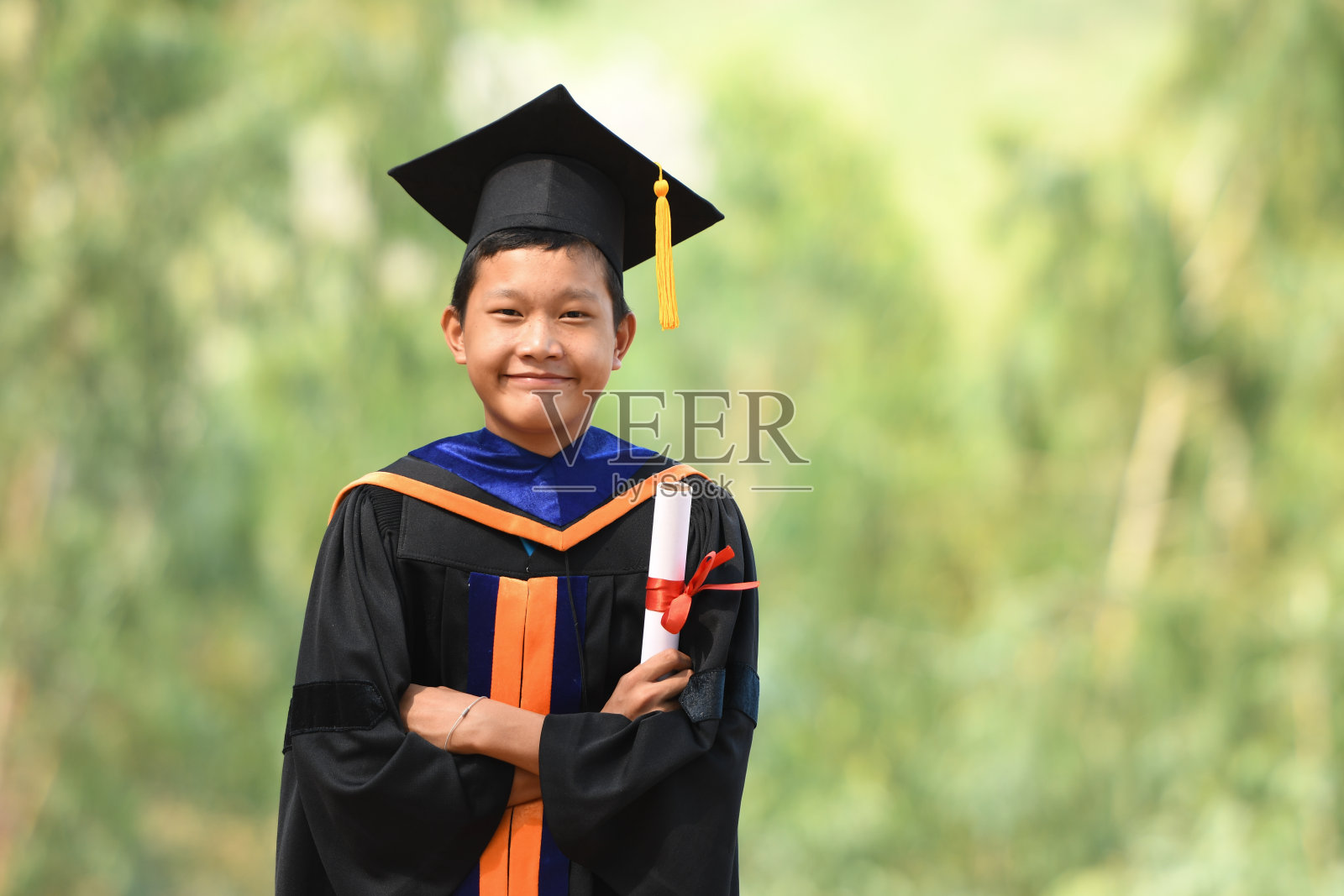 亚洲学生毕业典礼，身穿黑色褶边西装，头戴黑色帽子，配黄色流苏。照片摄影图片