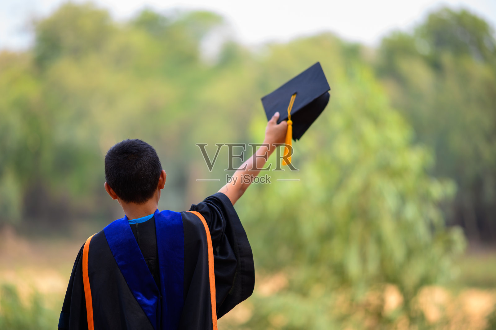 亚洲学生毕业典礼，身穿黑色褶边西装，头戴黑色帽子，配黄色流苏。照片摄影图片