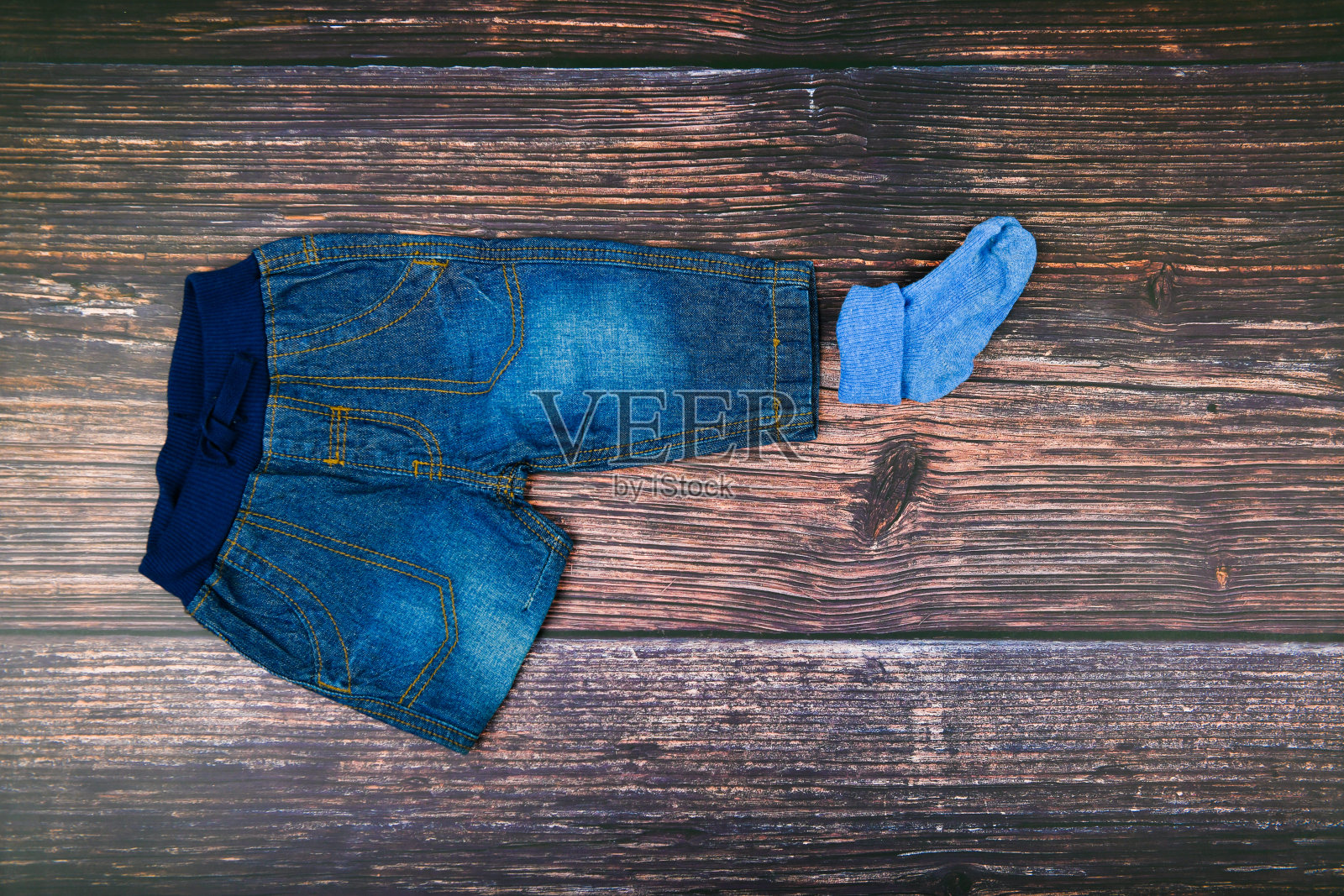 木制背景上的儿童牛仔裤。时尚的概念。服装的概念。深色木制背景。小男孩和牛仔裤。婴儿的衣服照片摄影图片