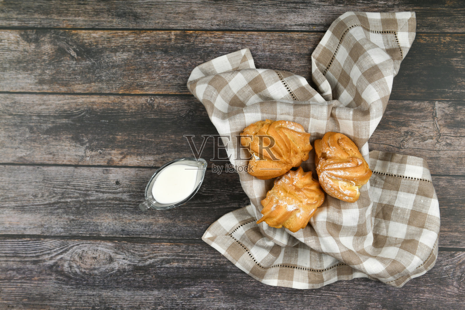 牛奶泡饼在深色的木制背景上。放在篮子里，放在格子毛巾上。从以上观点。别致的白软干酪。木背景柳条碗里的小蛋奶蛋糕照片摄影图片