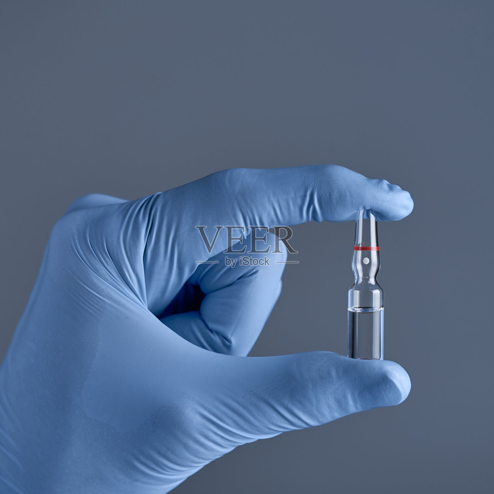 手拿医用蓝手套装安瓿。医疗帮助的概念。照片摄影图片