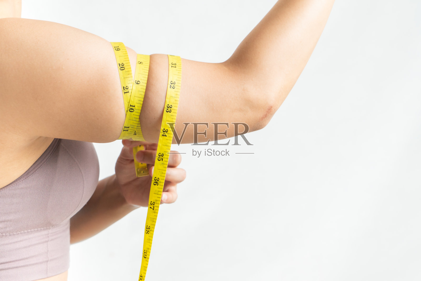 女人秀而捏紧，臂体脂肪由卷尺量度，女人饮食生活观念照片摄影图片